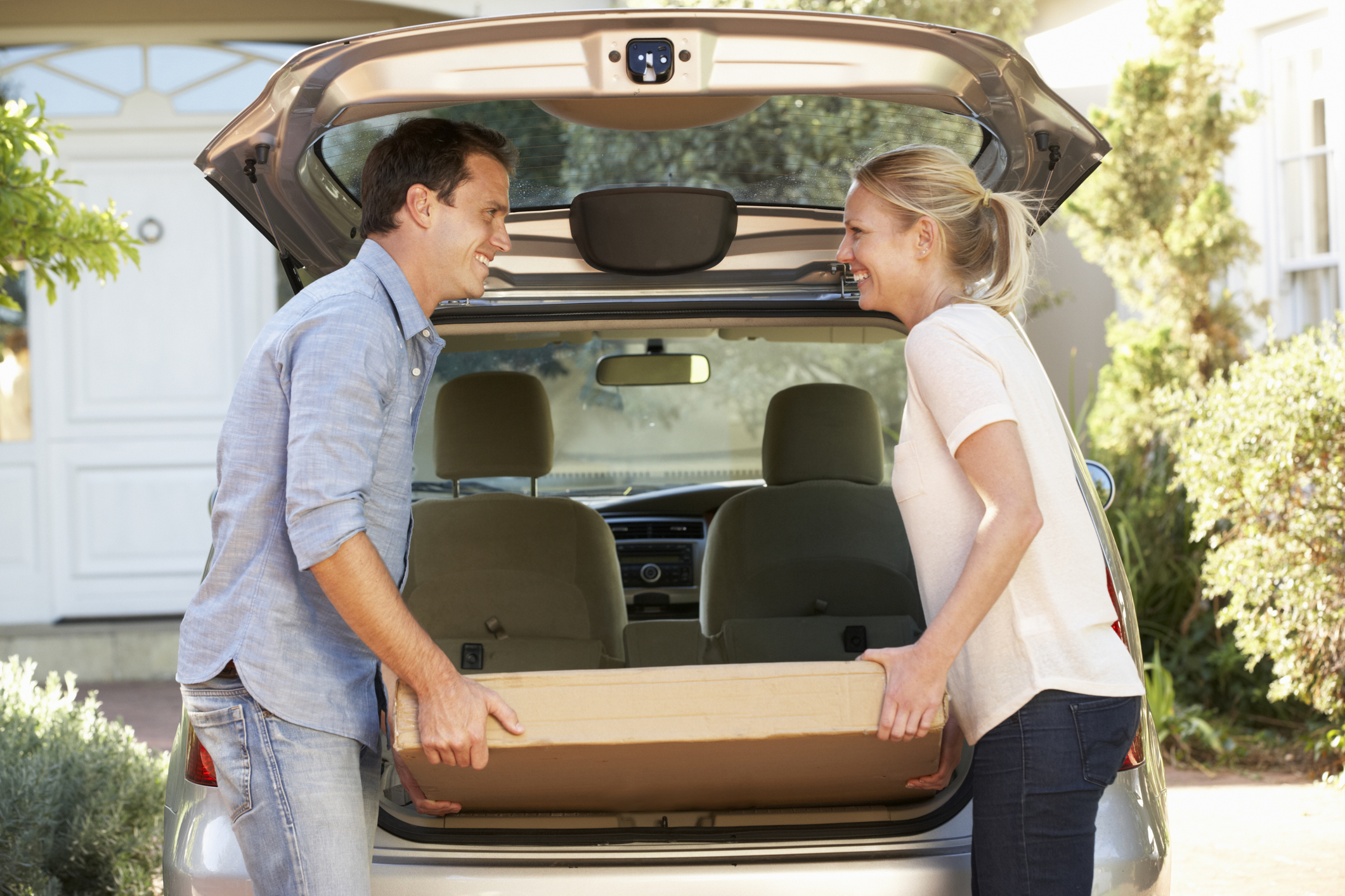 Couple Loading Large Package Into Back Of Car